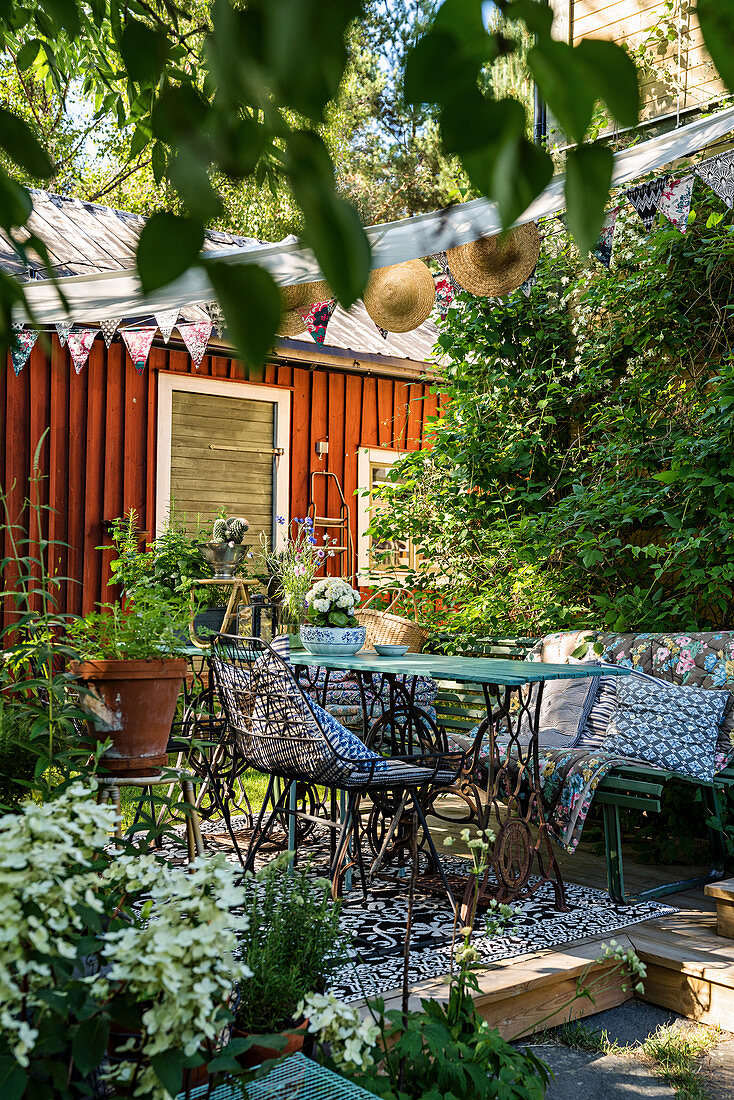 Nostalgische Gartenmöbel auf Holzterrasse in idyllisch sommerlichem Garten