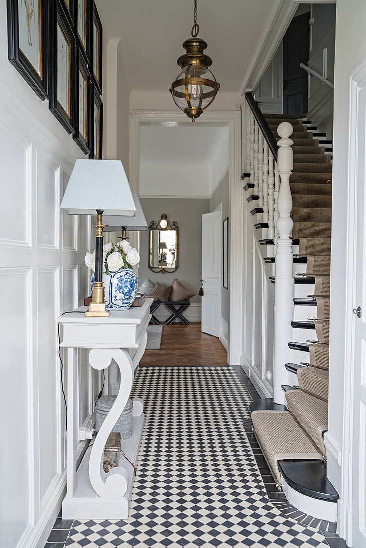 Console table on chequered floor in hallway with staircase