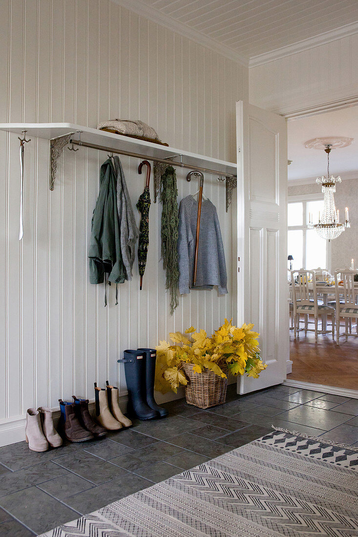 Weißer Holzverkleideter Flurbereich mit Garderobe und grauem Fliesenboden