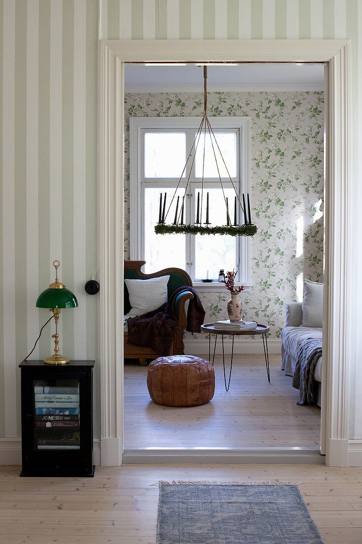 Blick in Wohnzimmer mit Hängekranz, Sofas und floraler Mustertapete