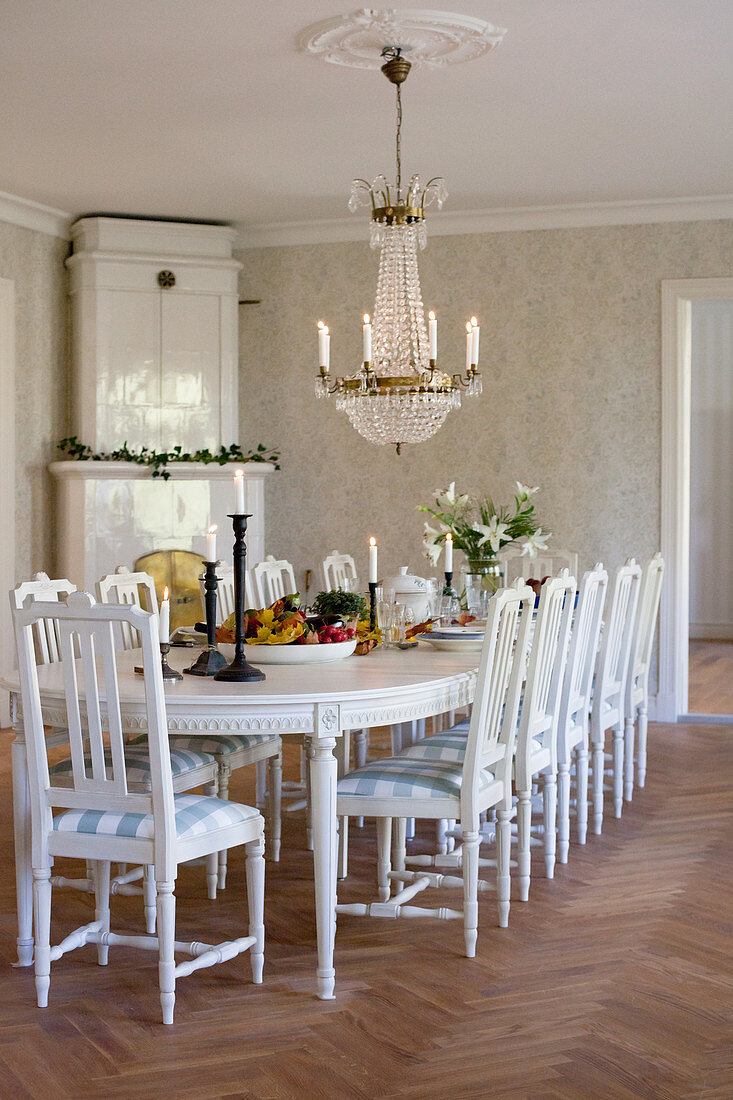 Eck-Kachelofen und großer weißer Esstisch mit Holzstühlen in Esszimmer eines Herrenhauses