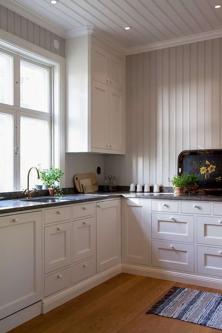 Geräumige weiße Landhausküche mit holzvertäfelten Wänden