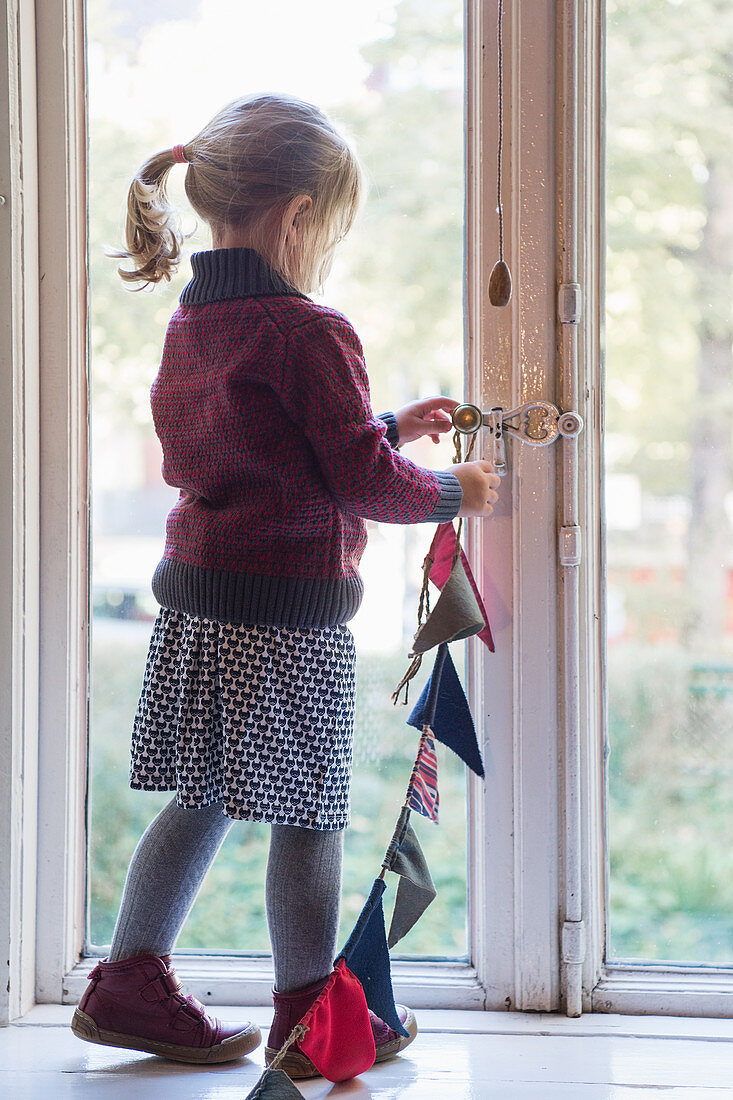 Mädchen hängt Wimpelkette ans Fenster