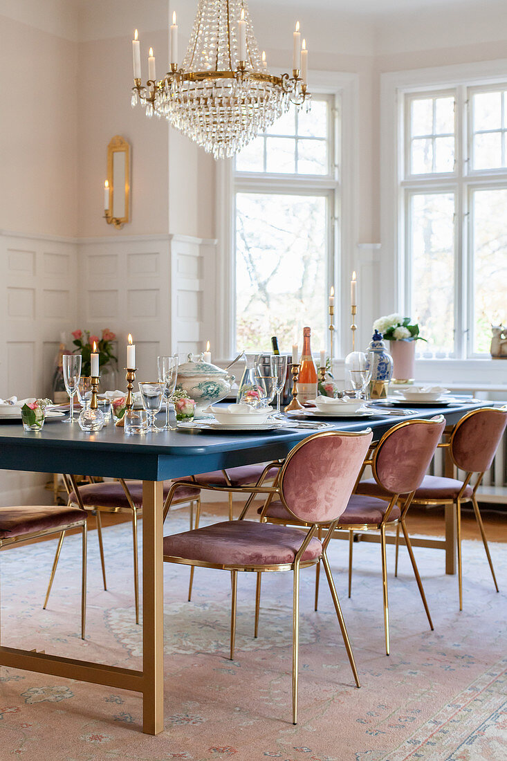 Velvet chairs around festively set dining table in glamorous dining room