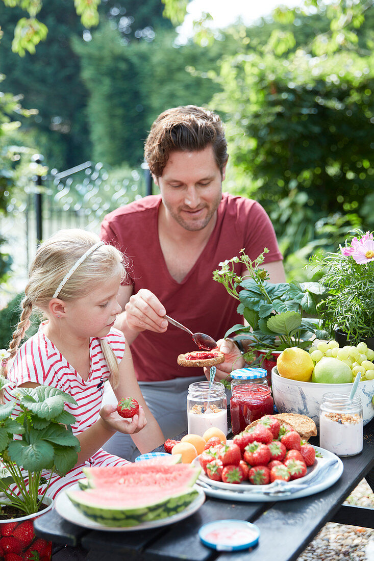Vater und Tochter beim Picknick mit Erdbeeren und Wassermelone
