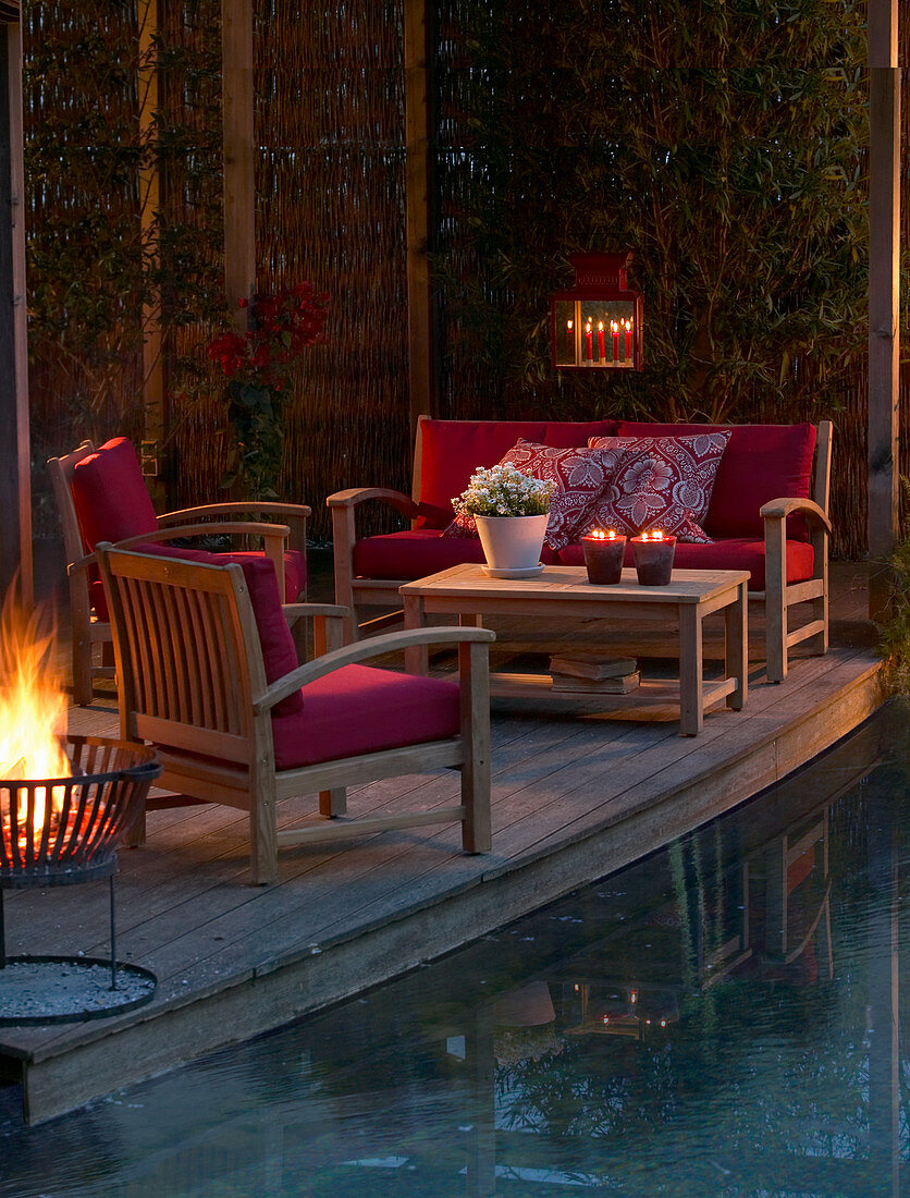 Lounge furniture on candlelit terrace next to pool at twilight