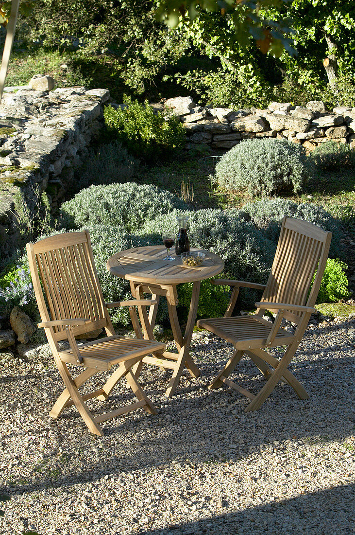 Sitzplatz mit Gartenmöbeln aus Holz im mediterranen Garten