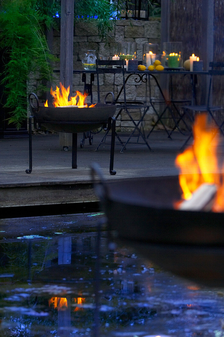 Feuerschalen um den Teich im abendlichen Garten