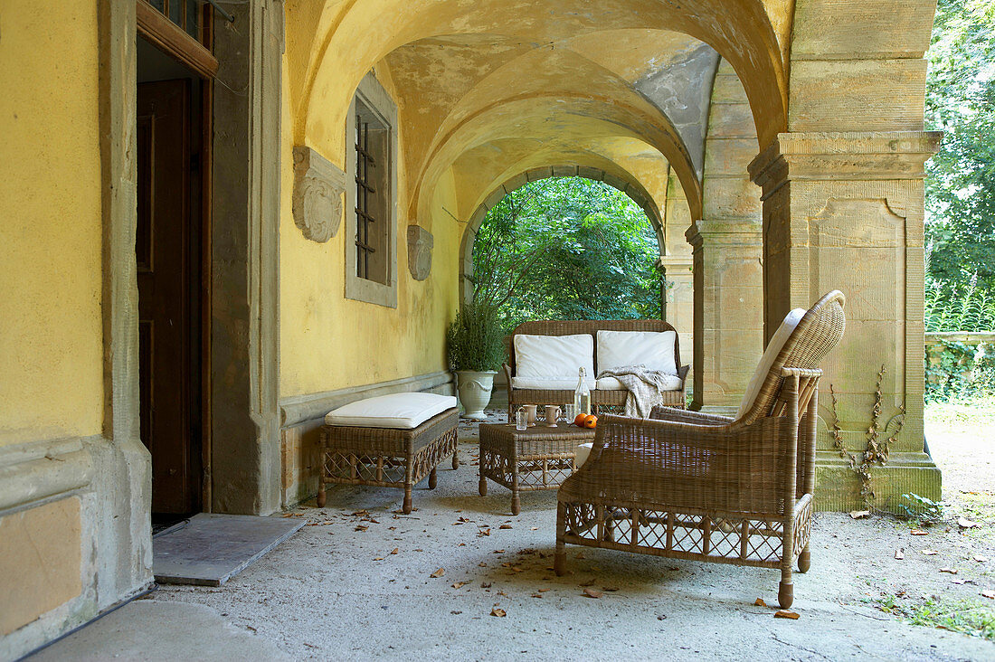 Wicker furniture in seating area under Mediterranean arcade