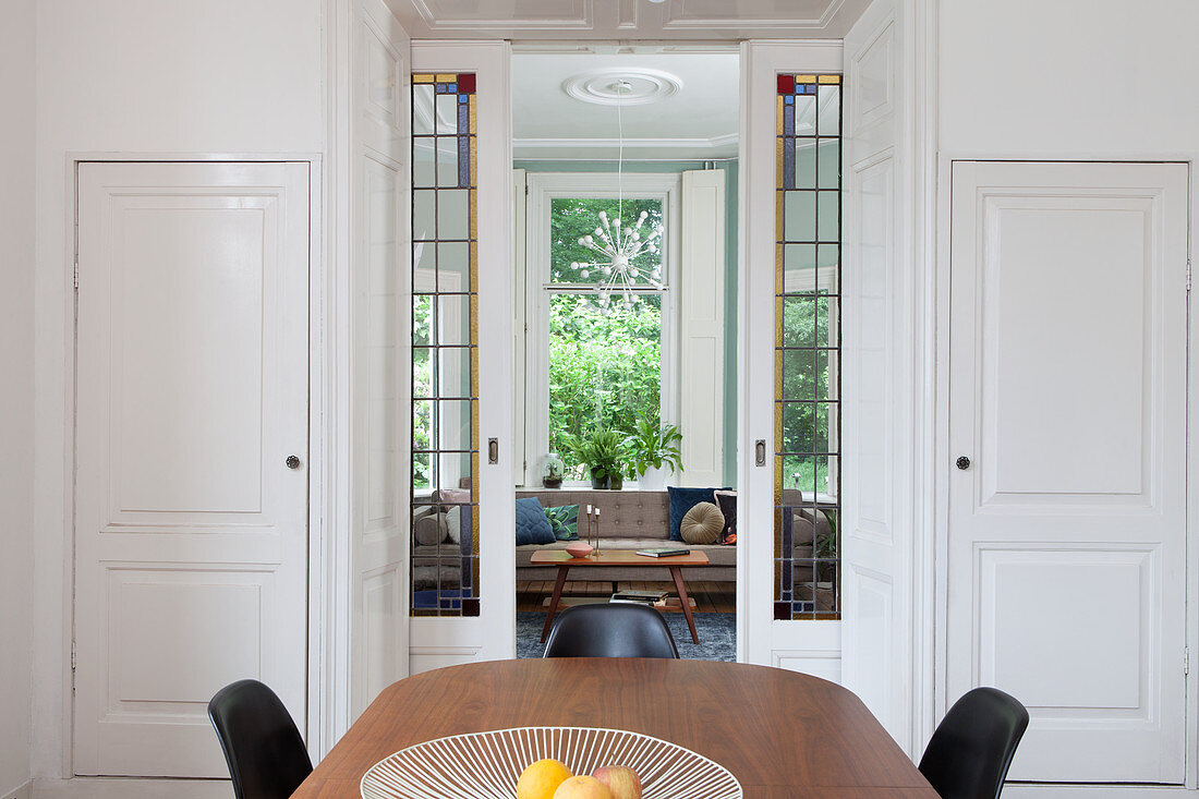 View through open, double, sliding doors with stained-glass inserts leading into living room