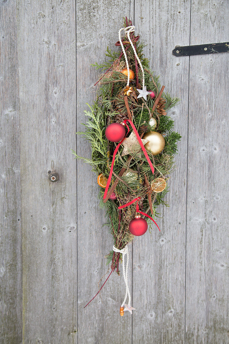 Festive teardrop wreath of conifer branches and baubles on door