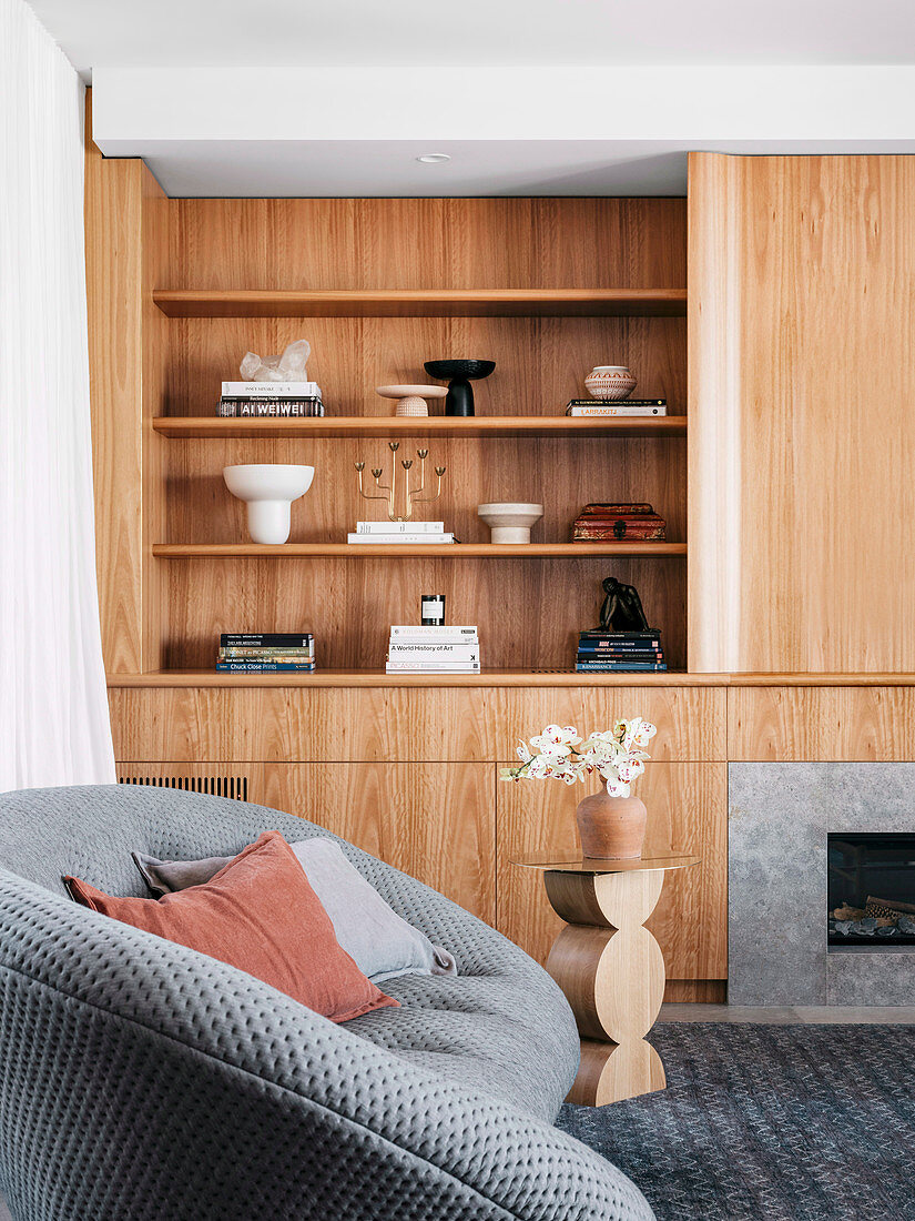 Eingebaute Wohnwand aus Holz im Wohnzimmer mit grauem Sofa