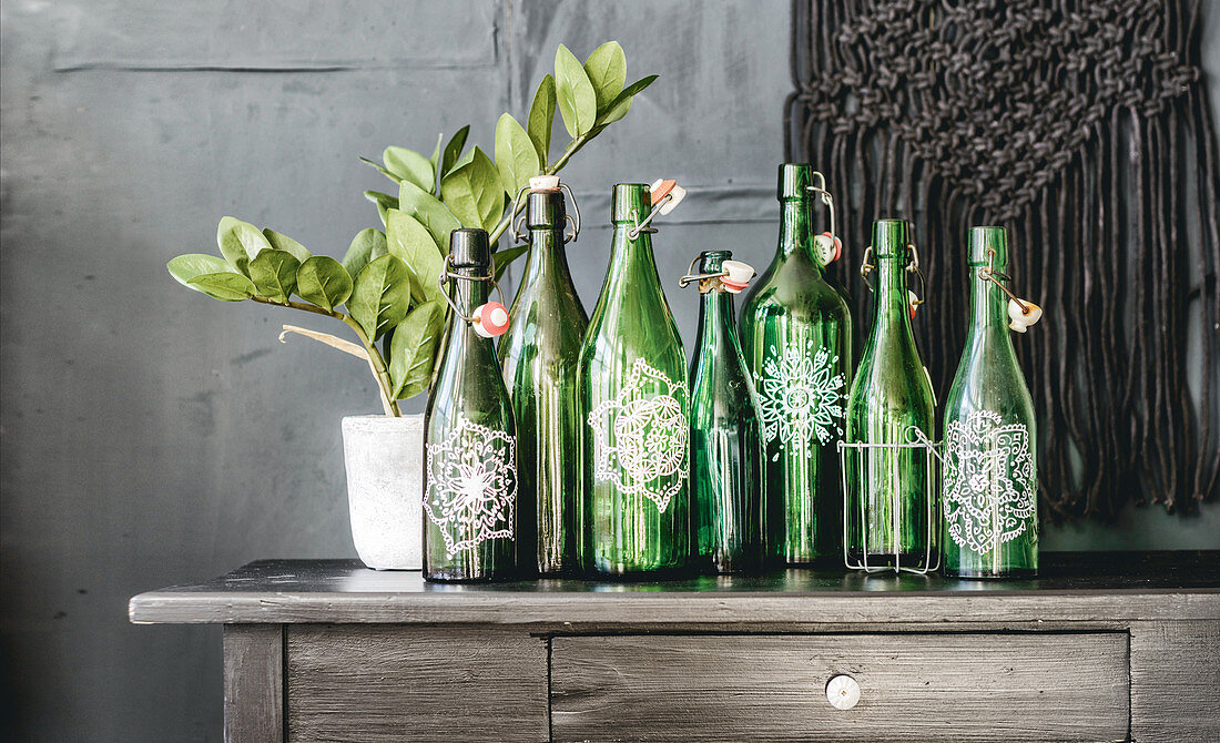 Arrangement of green glass bottles painted with mandalas