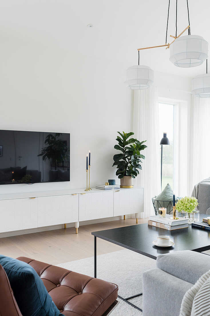 Wohnzimmer in Weiß-Grau mit Flachbildfernseher über niedriger TV-Kommode