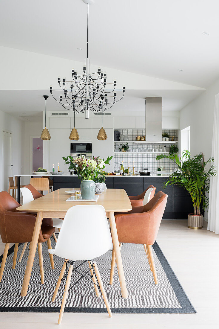 Dining table with classic chairs in open-plan interior with kitchen in background