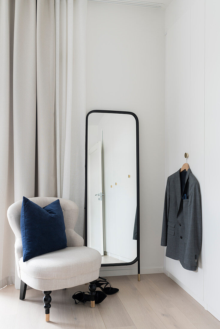 White easy chair, full-length mirror and clothes hook in corner