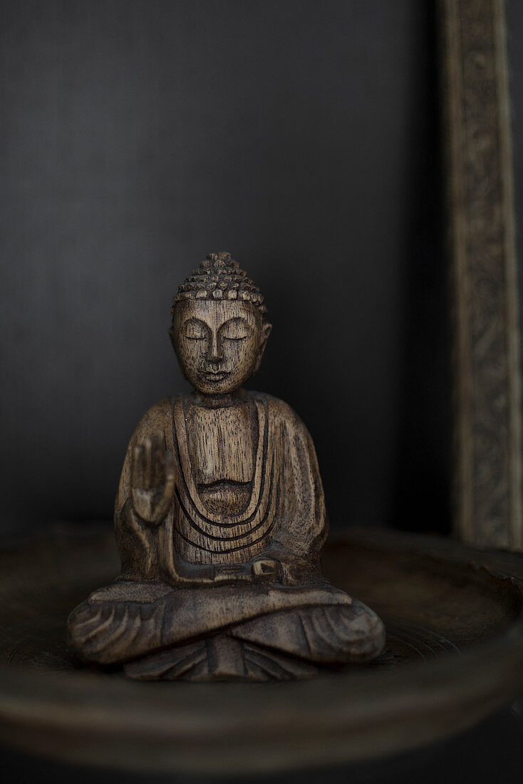 Buddha-Figur aus Holz vor schwarzem Hintergrund