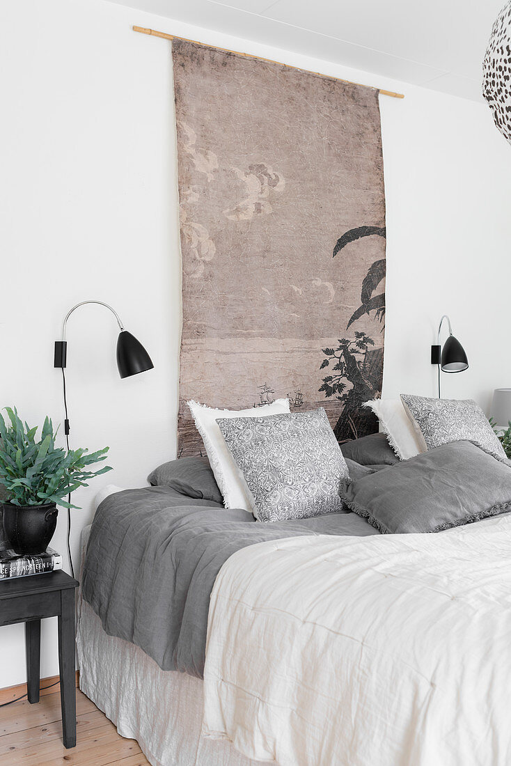 Oriental wall hanging and wall-mounted lamps above bed