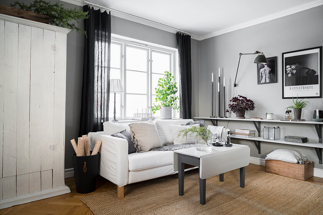 Wohnraum in Grau-Weiß mit Bauholzschrank, Sofa und niedgrigen Wandregalen