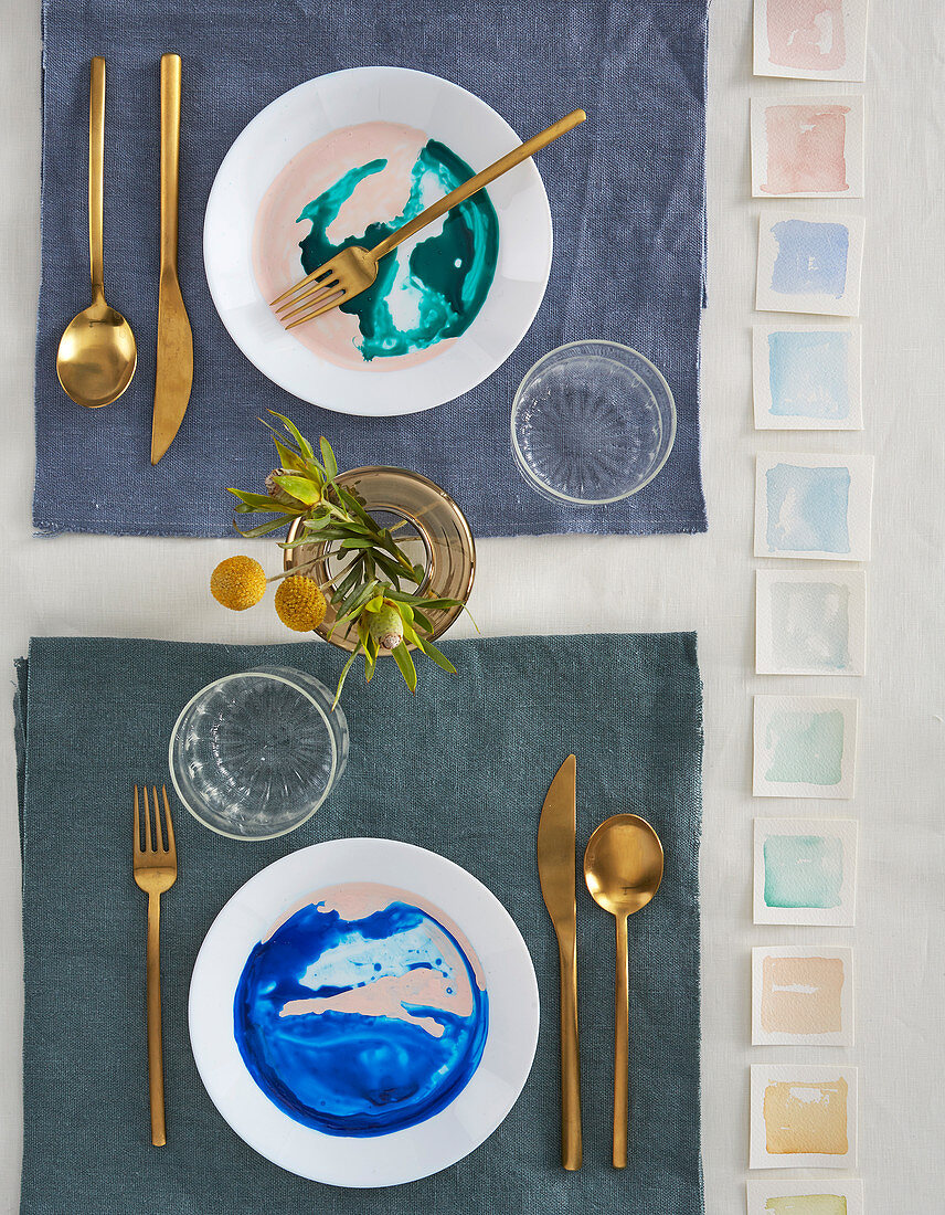 Watercolour-effect plates and gilt cutlery on set table
