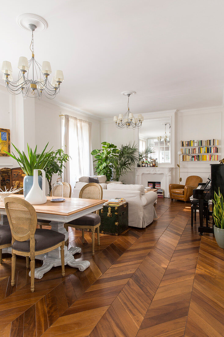 Dining table and herringbone parquet floor in open-plan living room of period building