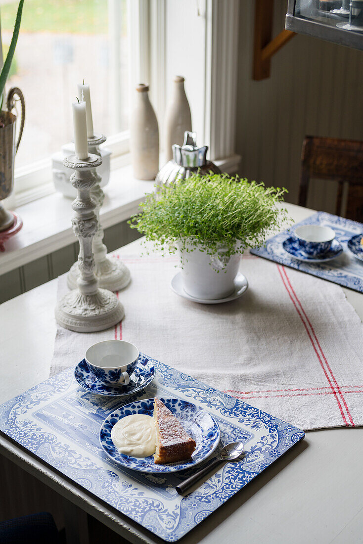 Gedeckter Kaffeetisch mit Tischsets und Geschirr in Blau-Weiß