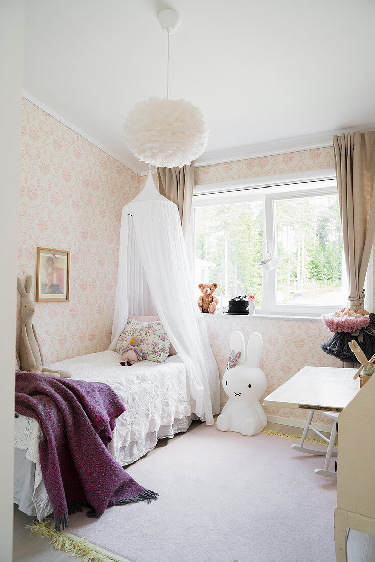 Canopied bed, large Miffy lamp and pastel wallpaper in girl's bedroom