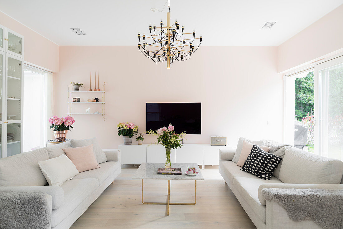 Sofagarnitur, Couchtisch und Fernsehmöbel im Wohnzimmer mit kühlen, rosa Wänden