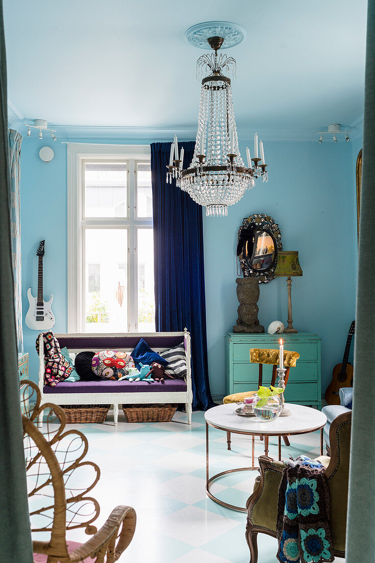 Antike Sitzbank neben Vintage-Kommode in Wohnraum mit blauen Wänden und Kronleuchter