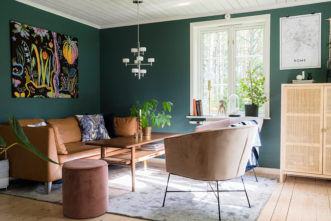 Sessel und Ledersofa um Couchtisch, moderne Kunsta an grüner Wand im Wohnzimmer