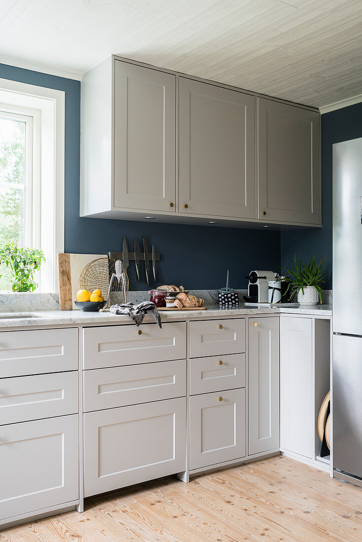 Weiße Schränke in Küche mit grau-blauer Wand