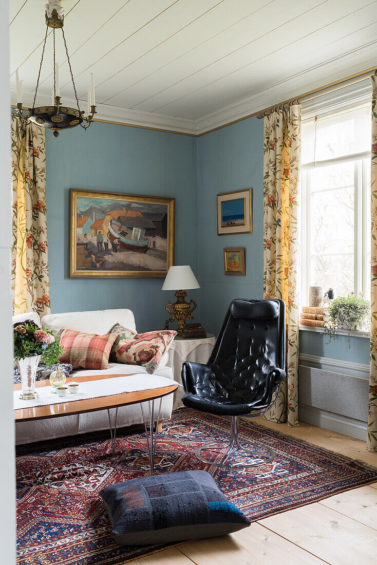 Black leather swivel armchair next to sofa in living room with blue walls