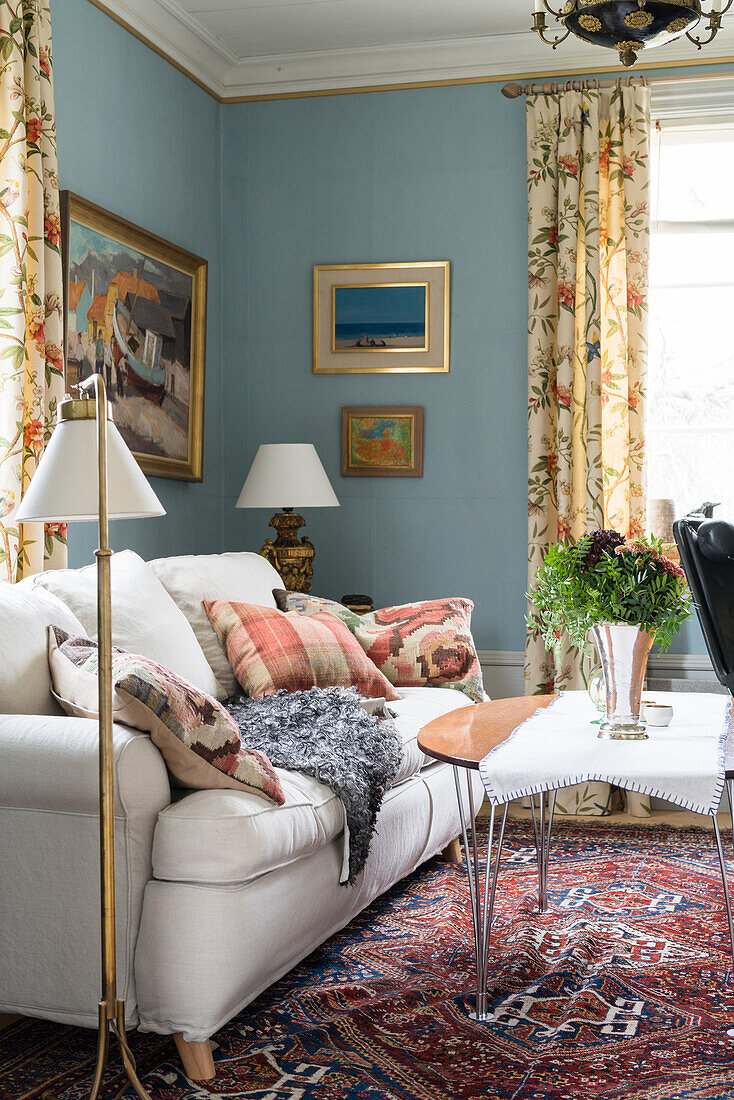 Cream sofa, standard lamp and coffee table in living room with blue walls