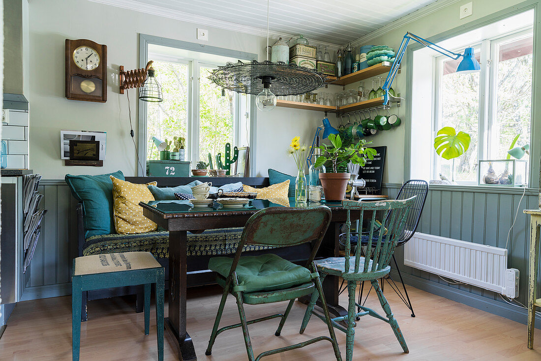 Esstisch in Zimmerecke mit Holzbank und verschiedenen Vintage-Sitzmöbeln