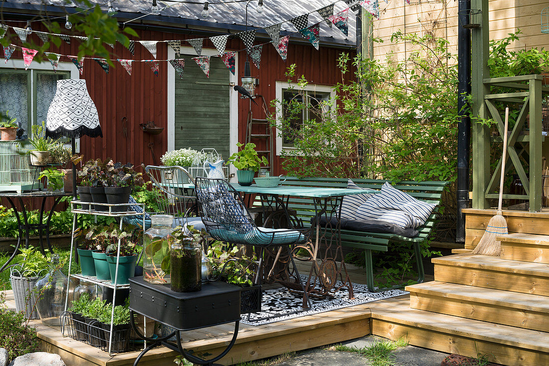 Wooden terrace decorated with potted plants and vintage-style garden furniture
