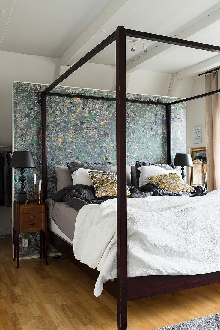 Four-poster bed with dark wooden frame against partition wall