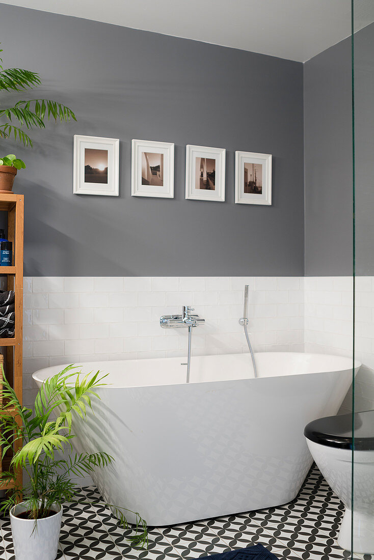 Moderne freistehende Wanne in Bad mit grauen Wänden und schwarz-weißem Fliesenboden