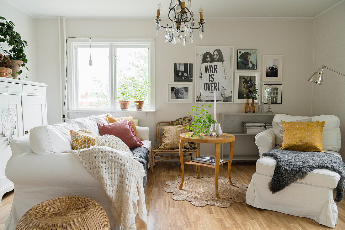 Sofa und Sessel mit weißen Hussen und runder Tisch im Wohnzimmer im Landhausstil