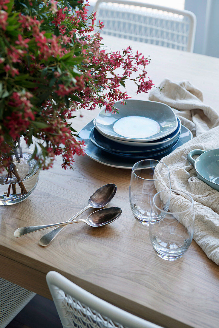 Silberlöffel, Gläser und rustikales blaues Geschirr auf dem Holztisch