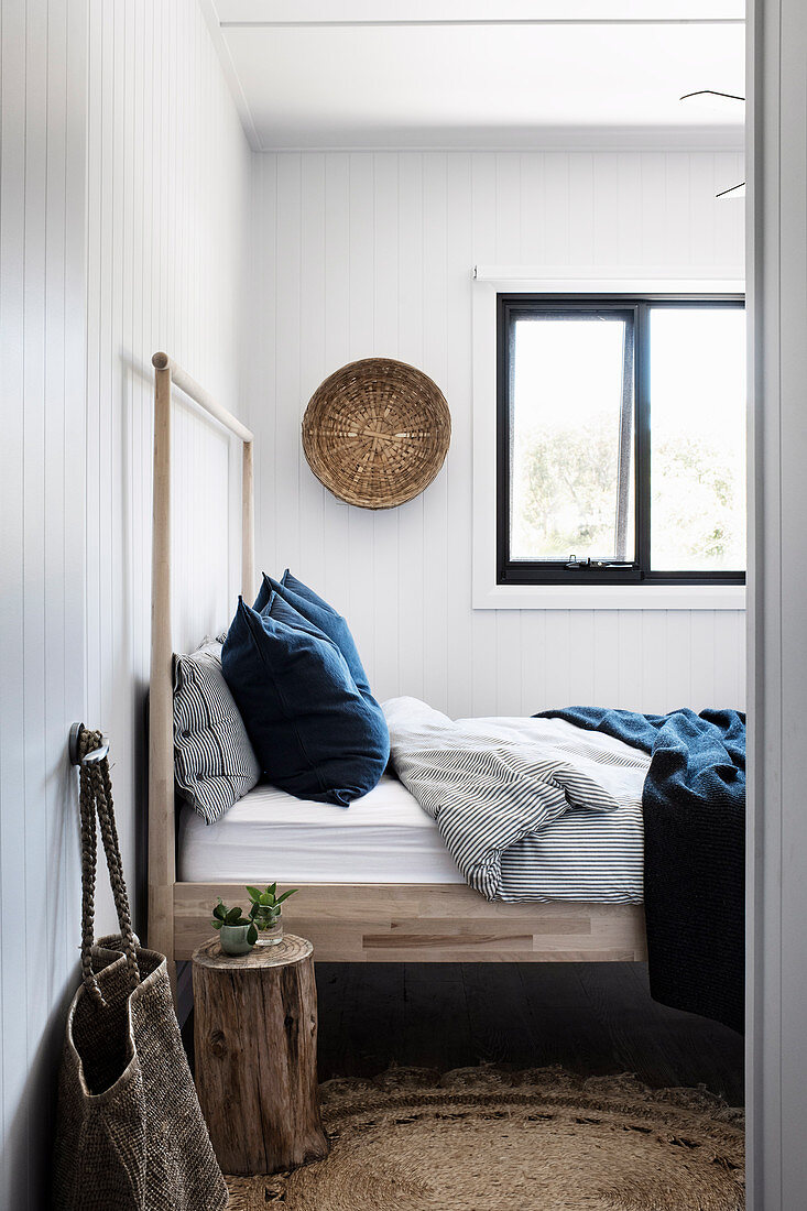 Holzbett im schlichten Schlafzimmer mit Naturmaterialien