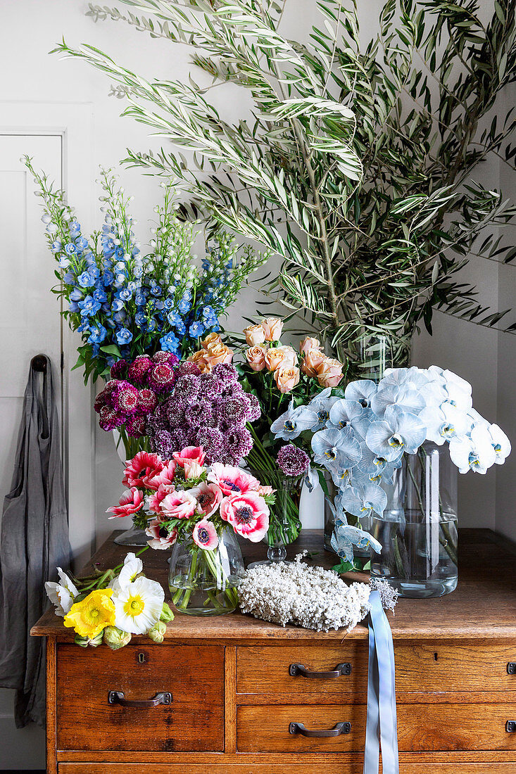 Olive branches and various flowers in glass vases