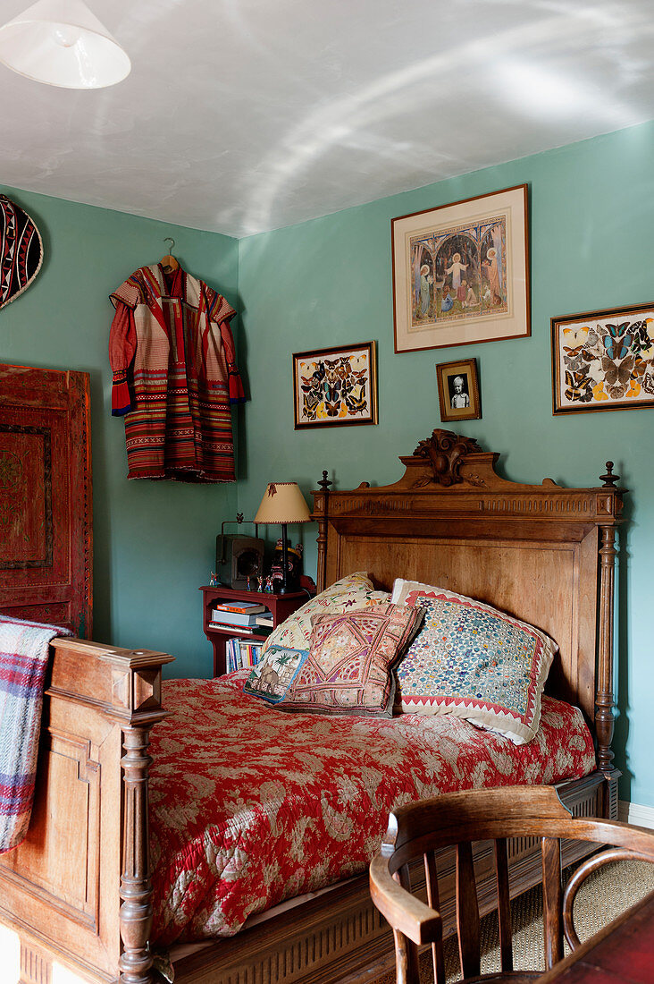 Antikes Holzbett in Schlafraum mit türkisfarbenen Wänden in englischem Landhaus