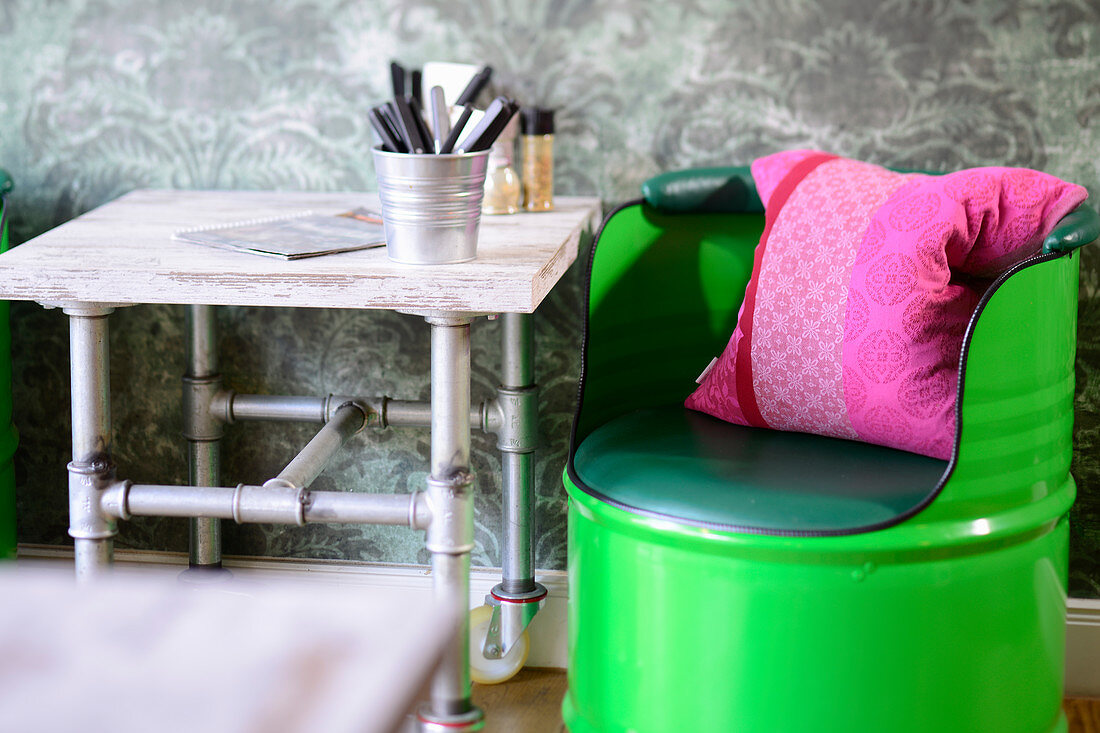 Green-painted barrel chair and vintage-style table made from steel pipes