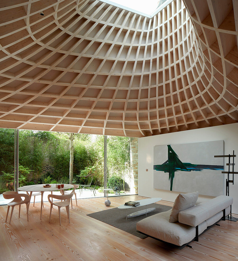 Minimalist living room in modern extension with glass walls and funnel-shaped roof