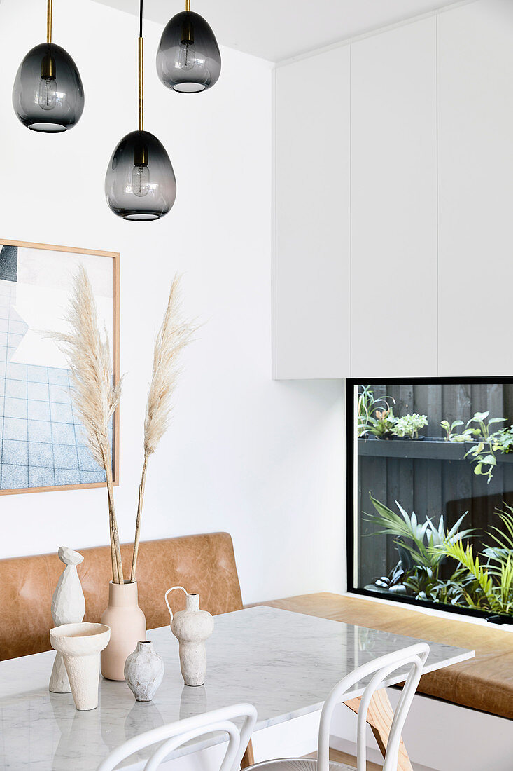 Wohnraum mit Marmor-Esstisch und eingebautem Pflanzenterrarium als Wanddekoration