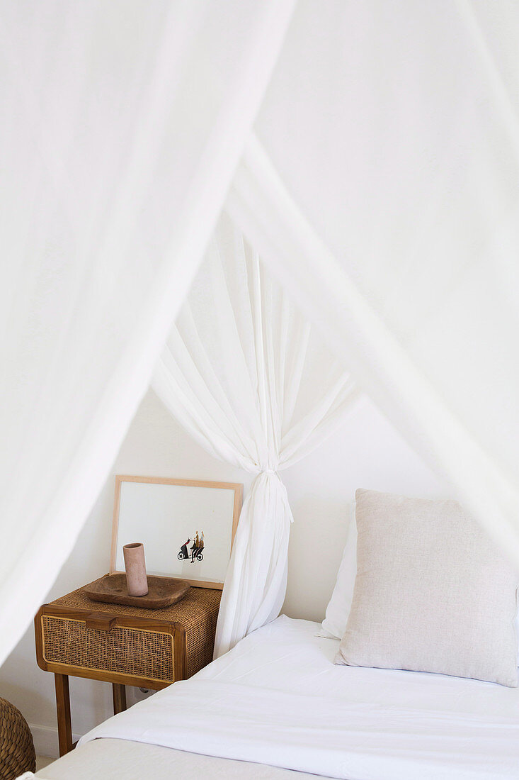 Rustic bedside table next to the bed with white canopy