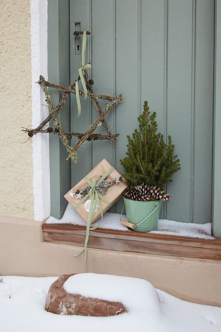 Geschenk, Bäumchen und Stern aus Zweigen mit Flechten an der Tür