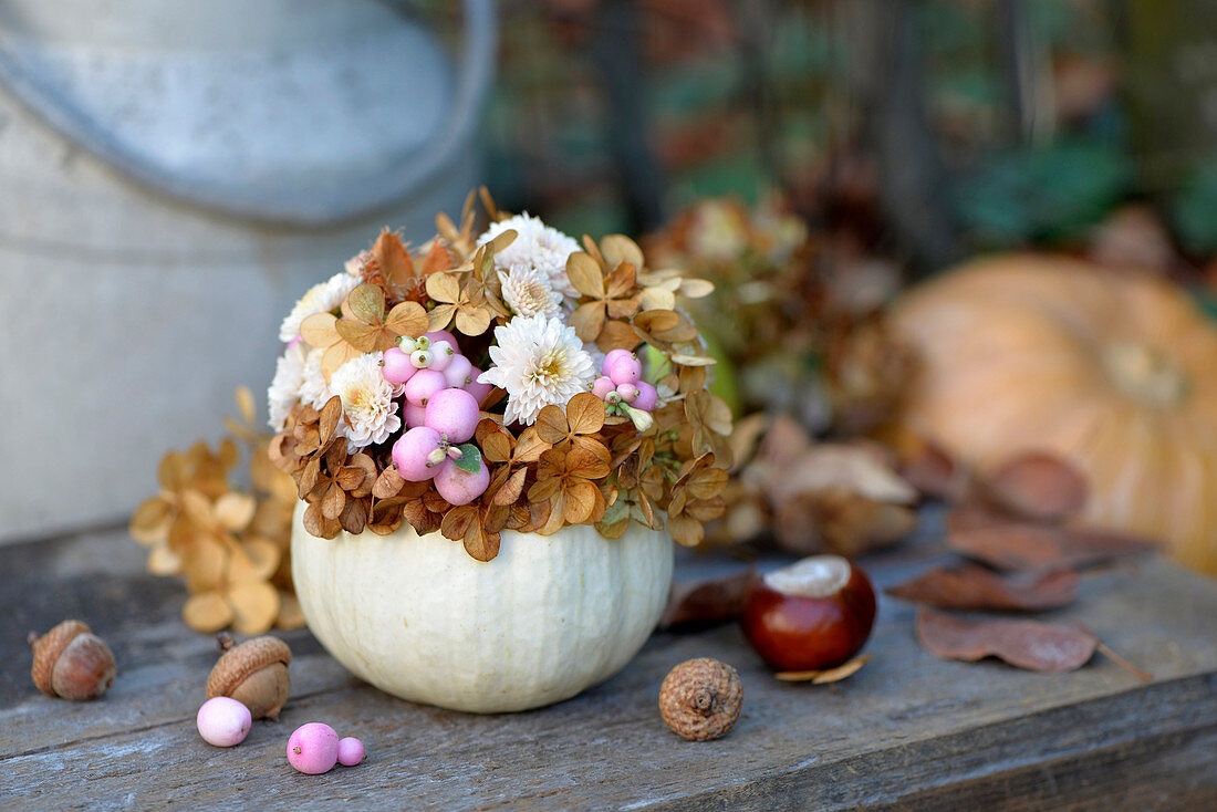 Ornamental gourd used as vase for chrysanthemums, snowberries and dried hydrangea florets