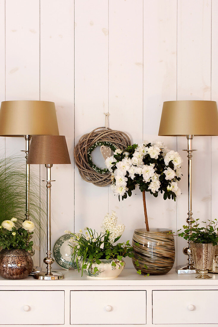 Potted azalea surrounded by gold table lamps