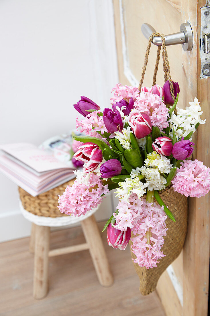 Frühlingsstrauß mit Hyazinthen und Tulpen in Tasche an Türe gehängt